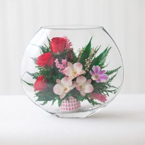 Розовато-белые и фиолетовые орхидеи с красными розами в малой плоской круглой вазе